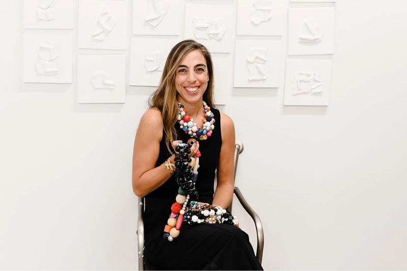 Alice, surrounded by her own work and wearing the beaded necklaces that inspired the design